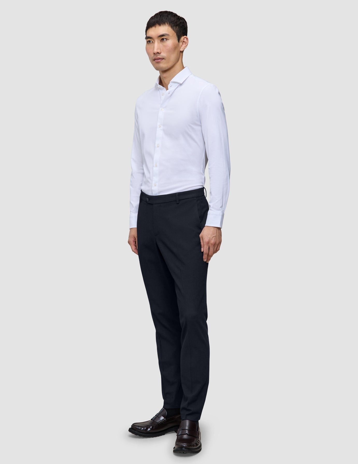 En mann i en hvit skjorte med knapper og Motion Suit-bukser i slim-passform i midnattsblått.